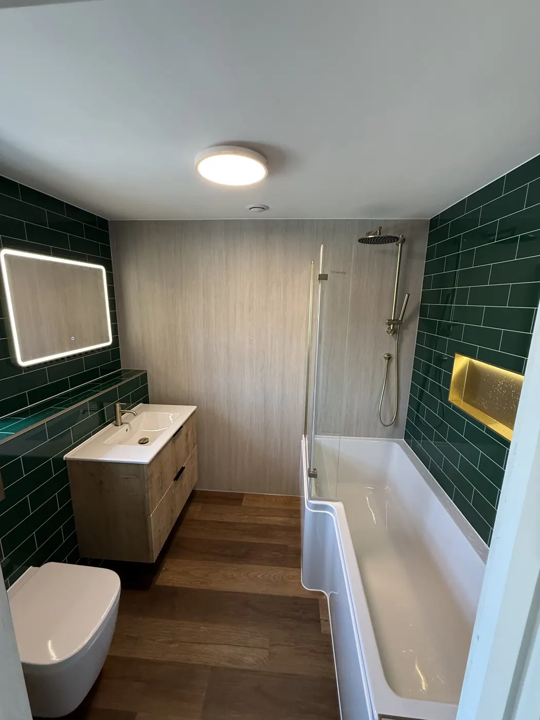 Full bathroom installation with green metro tiles and brushed brass fittings