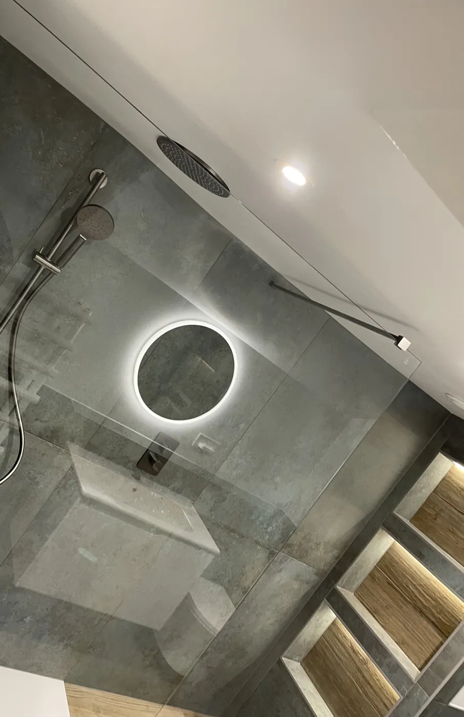 Modern bathroom with large-format tiles, matt black shower and lit niches