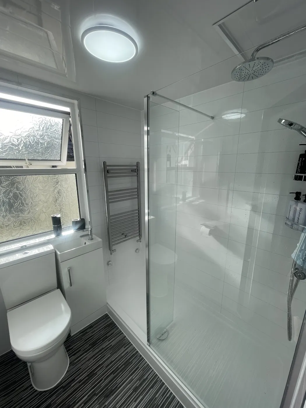 Bright shower room with walk-in screen, rainfall shower and towel radiator